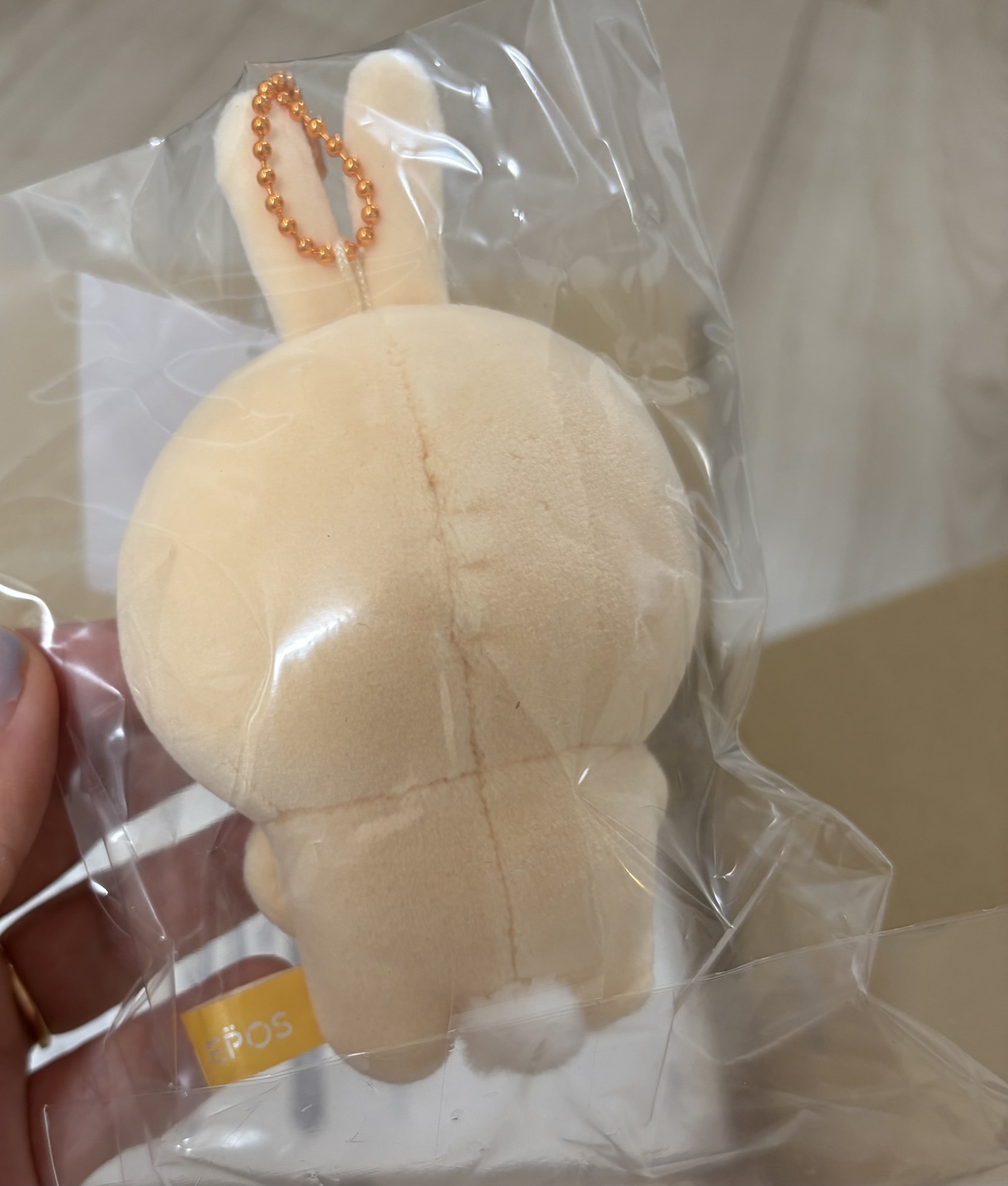うさぎおかいもの検定マスコットの後ろ姿。耳の間からオレンジ色のボールチェーンが出ていて、袋にはEPOSのシールが貼られている